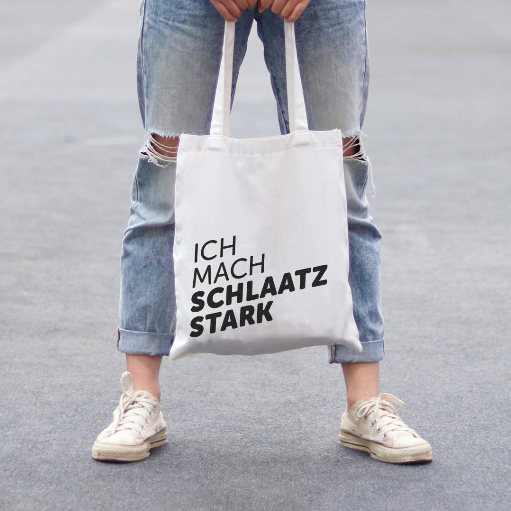 Ich mach Schlaatz stark: Frau mit Jeans und bedrucktem Beutel; Markenkommunikation, Branding, Logo