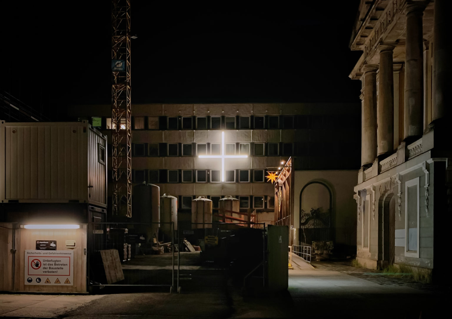 Blick auf den Bereich zwischen der Garnisonkirche, der Nagelkreuzkapelle und dem Rechenzentrum – Kunst- und Kreativhaus. Acht leuchtende LED-Lampen in Form eines Plus an der Fassade des Rechenzentrum.