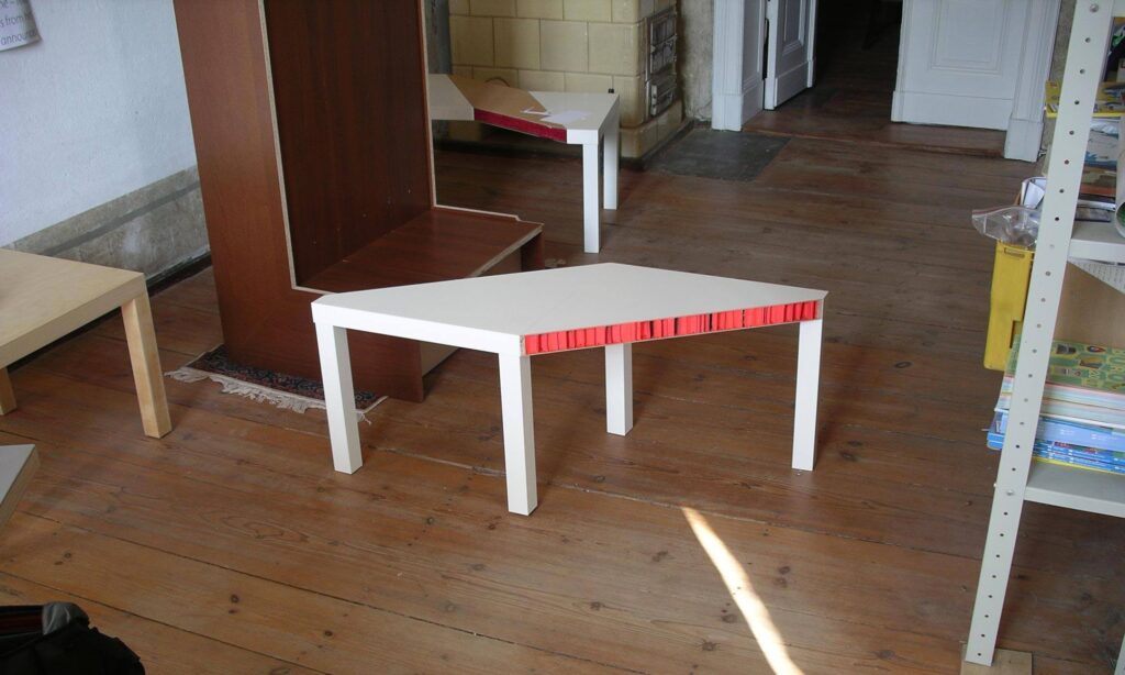 Weißer Tisch mit roter offener Kante, industrielle Oberfläche und sichtbare innere Materialstruktur.