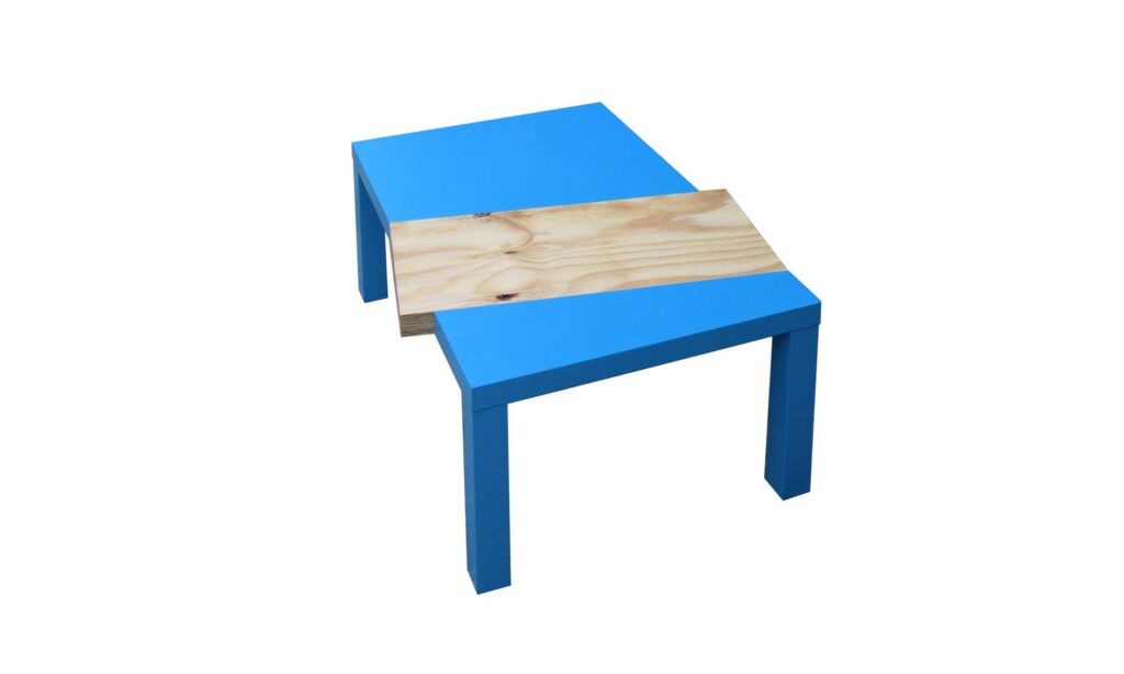 Blauer Tisch mit eingesetztem Holzbrett, Kontrast von industrieller Farbe und organischer Maserung.
