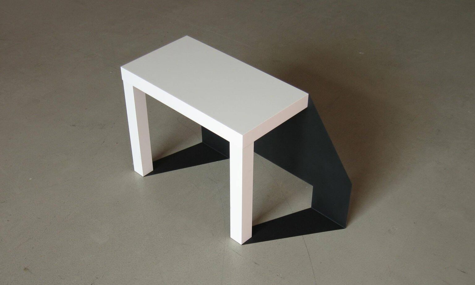 Tischobjekt mit schwarzem Volumen und weißer Platte, Untersuchung von Form, Funktion und Schatten.